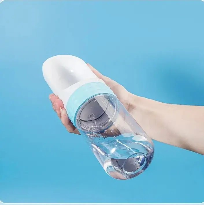 Hand tilting the bottle so leftover water drains from the scoop back into the tank.