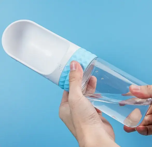 Two hands twisting the textured blue collar of the bottle from OFF to ON as water fills the scoop.